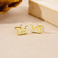 Woman wearing 14K gold crown stud earrings as part of a curated ear stack