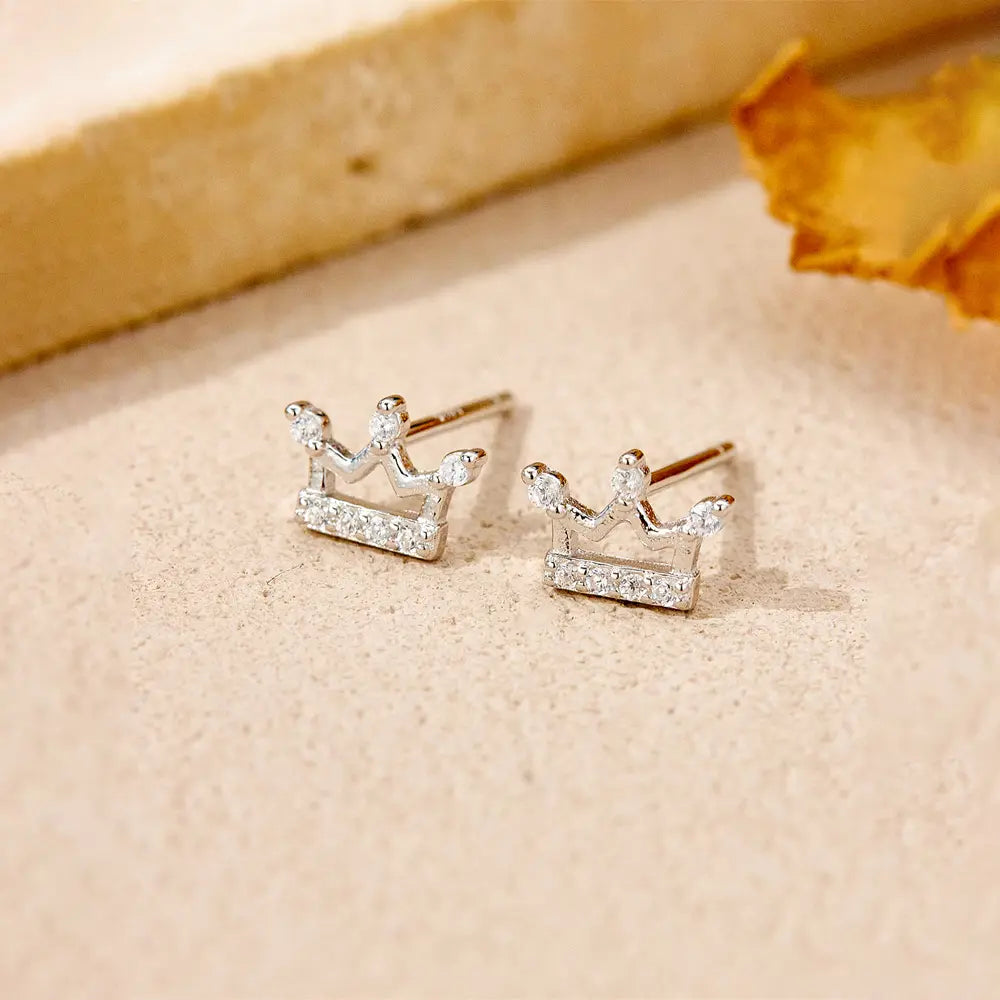 Woman wearing 925 silver crown stud earrings as part of a curated ear stack