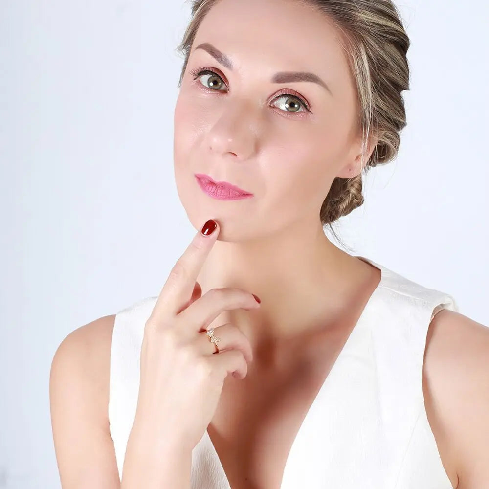 Studijinis viršutinis kadras: rodižu padengtas 925 sidabro drugelio filigrano žiedas ant švaraus balto fono; matoma visa juostelė ir drugelis su AAAAA kubiniu cirkoniu. Pažymėtas Loretana kūrinys, rankomis užbaigtas Kaune.