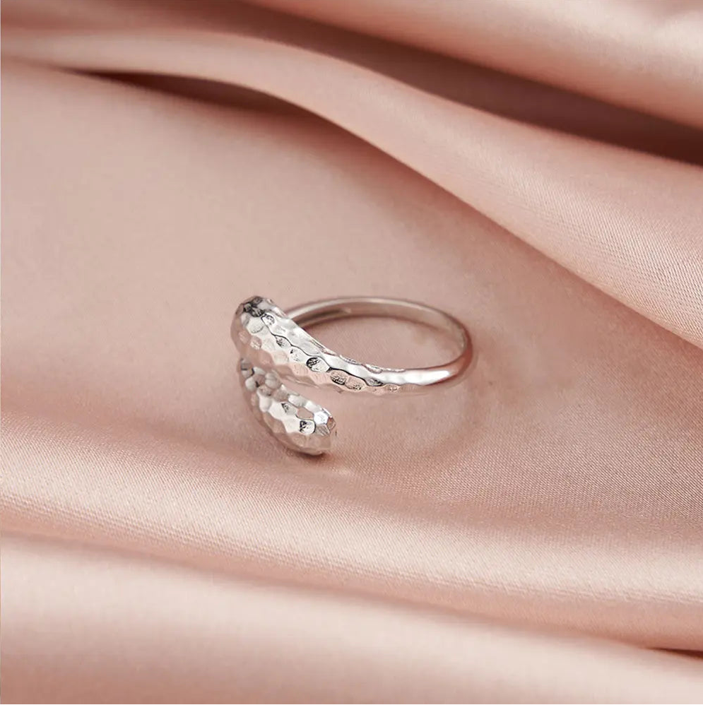 Hand model wearing the silver hammered double teardrop adjustable ring in 925 sterling silver with rhodium plating, open back visible behind the finger in soft daylight. Hallmarked Loretana piece, hand-finished in Kaunas.